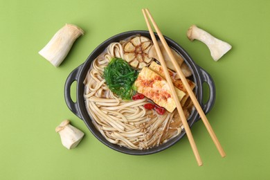 Photo of Tasty ramen with enoki and king oyster (eryngii) mushrooms on green background, flat lay