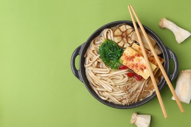 Photo of Tasty ramen with enoki and king oyster (eryngii) mushrooms on green background, flat lay. Space for text