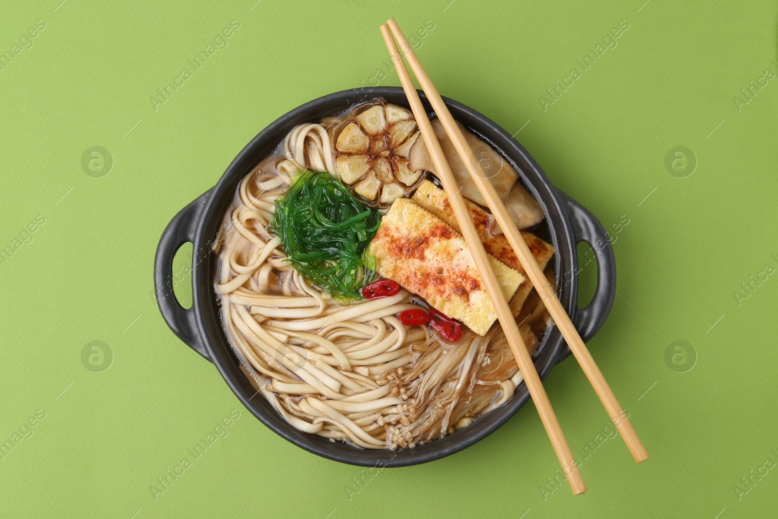Tasty ramen with enoki and king oyster (eryngii) mushrooms on green background, top view Photo of Tasty ramen with enoki and king oyster (eryngii) mushrooms on green background, top view