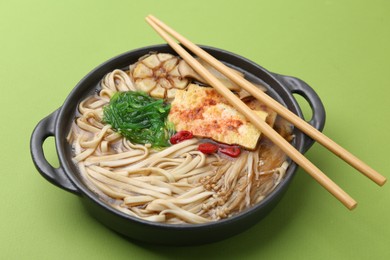 Photo of Tasty ramen with enoki and king oyster (eryngii) mushrooms on green background, closeup