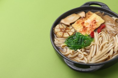 Photo of Tasty ramen with enoki and king oyster (eryngii) mushrooms on green background, closeup. Space for text