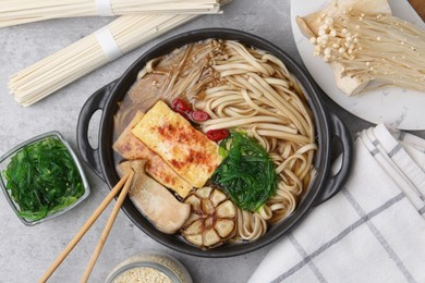 Photo of Tasty ramen with enoki and king oyster (eryngii) mushrooms on light grey table, flat lay