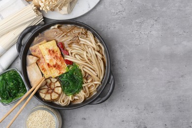 Photo of Tasty ramen with enoki and king oyster (eryngii) mushrooms on light grey table, flat lay. Space for text