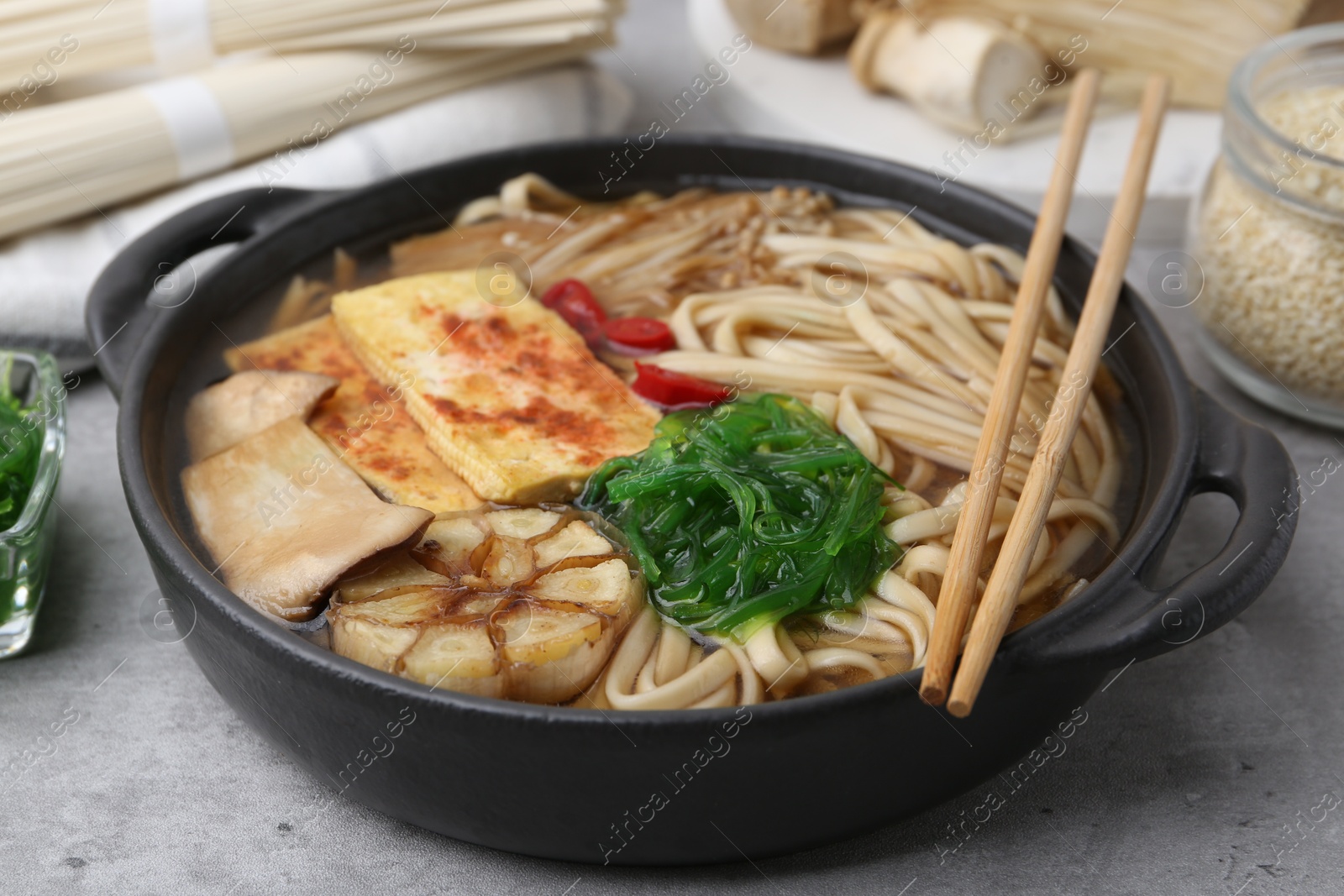 Tasty ramen with enoki and king oyster (eryngii) mushrooms on light grey table, closeup Photo of Tasty ramen with enoki and king oyster (eryngii) mushrooms on light grey table, closeup