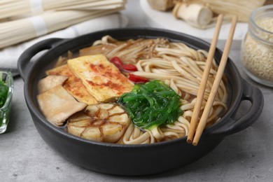 Photo of Tasty ramen with enoki and king oyster (eryngii) mushrooms on light grey table, closeup