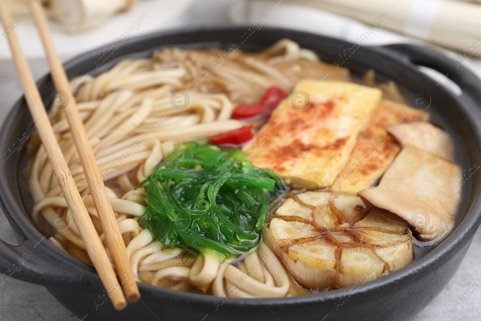 Tasty ramen with enoki and king oyster (eryngii) mushrooms on light grey table, closeup Photo of Tasty ramen with enoki and king oyster (eryngii) mushrooms on light grey table, closeup