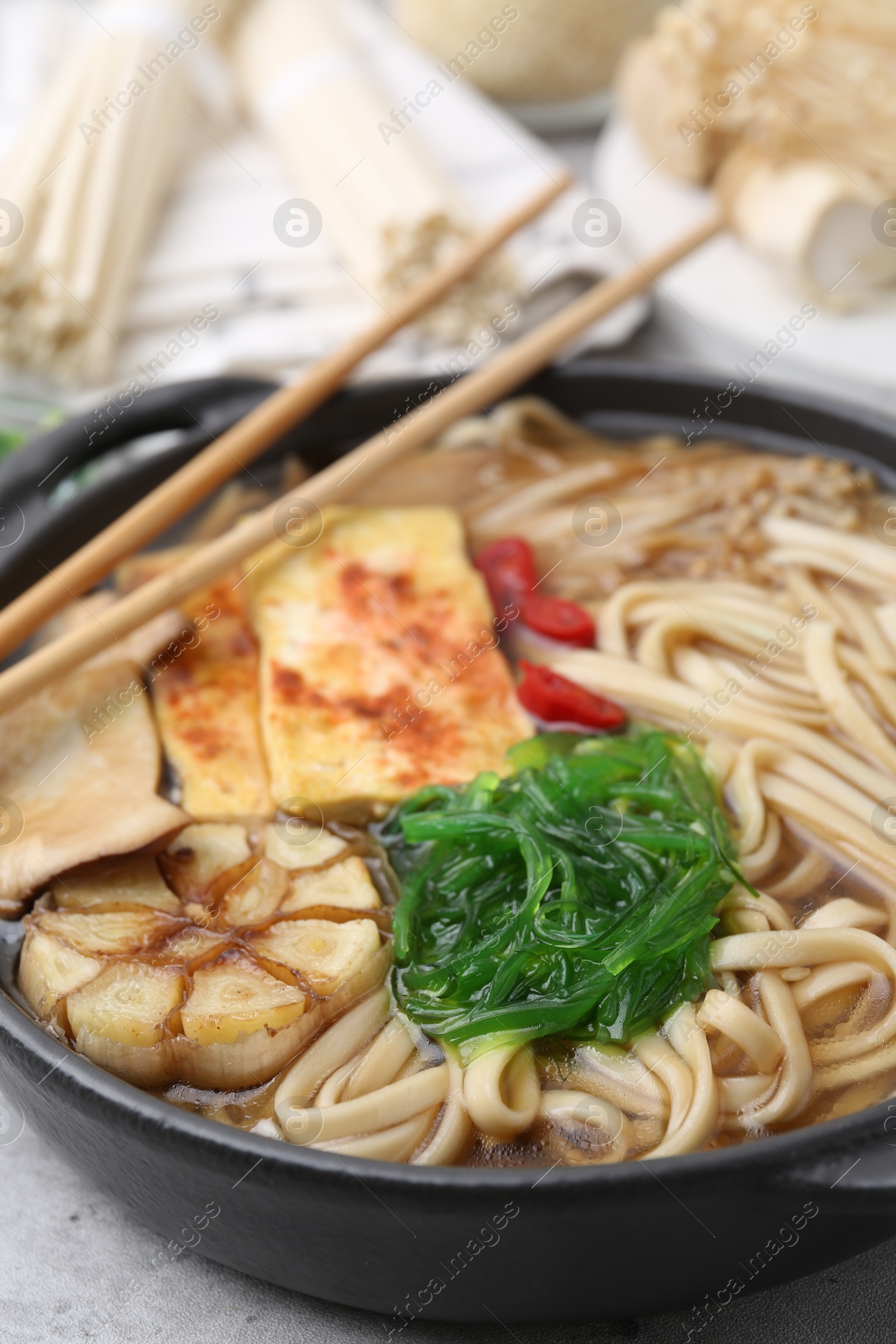Tasty ramen with enoki and king oyster (eryngii) mushrooms on light grey table, closeup Photo of Tasty ramen with enoki and king oyster (eryngii) mushrooms on light grey table, closeup