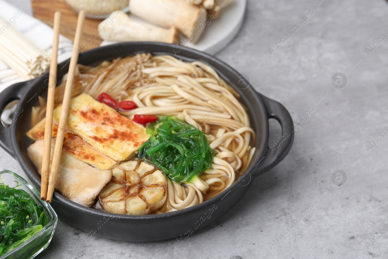 Tasty ramen with enoki and king oyster (eryngii) mushrooms on light grey table, closeup Photo of Tasty ramen with enoki and king oyster (eryngii) mushrooms on light grey table, closeup