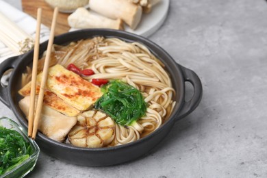 Photo of Tasty ramen with enoki and king oyster (eryngii) mushrooms on light grey table, closeup