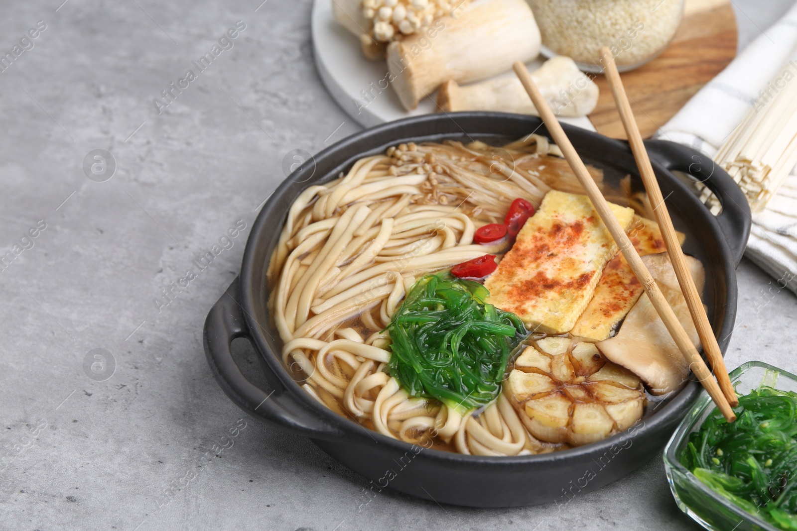 Tasty ramen with enoki and king oyster (eryngii) mushrooms on light grey table, closeup Photo of Tasty ramen with enoki and king oyster (eryngii) mushrooms on light grey table, closeup