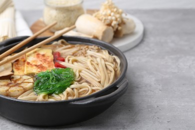 Photo of Tasty ramen with enoki and king oyster (eryngii) mushrooms on light grey table, closeup. Space for text