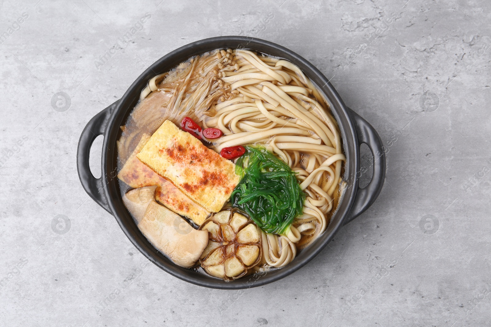 Tasty ramen with enoki and king oyster (eryngii) mushrooms on light grey table, top view Photo of Tasty ramen with enoki and king oyster (eryngii) mushrooms on light grey table, top view