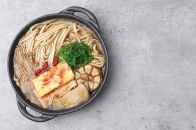 Photo of Tasty ramen with enoki and king oyster (eryngii) mushrooms on light grey table, top view. Space for text