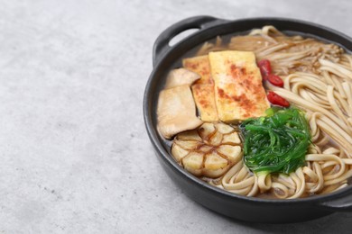 Photo of Tasty ramen with enoki and king oyster (eryngii) mushrooms on light grey table, closeup. Space for text
