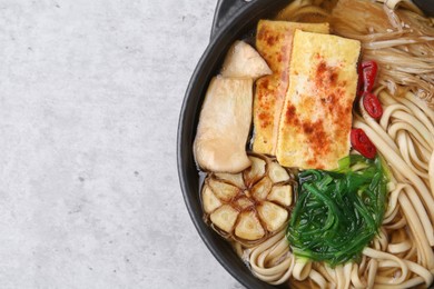Photo of Tasty ramen with enoki and king oyster (eryngii) mushrooms on light grey table, top view. Space for text