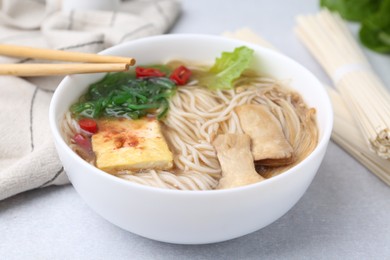 Photo of Tasty ramen with enoki and king oyster (eryngii) mushrooms on white table, closeup