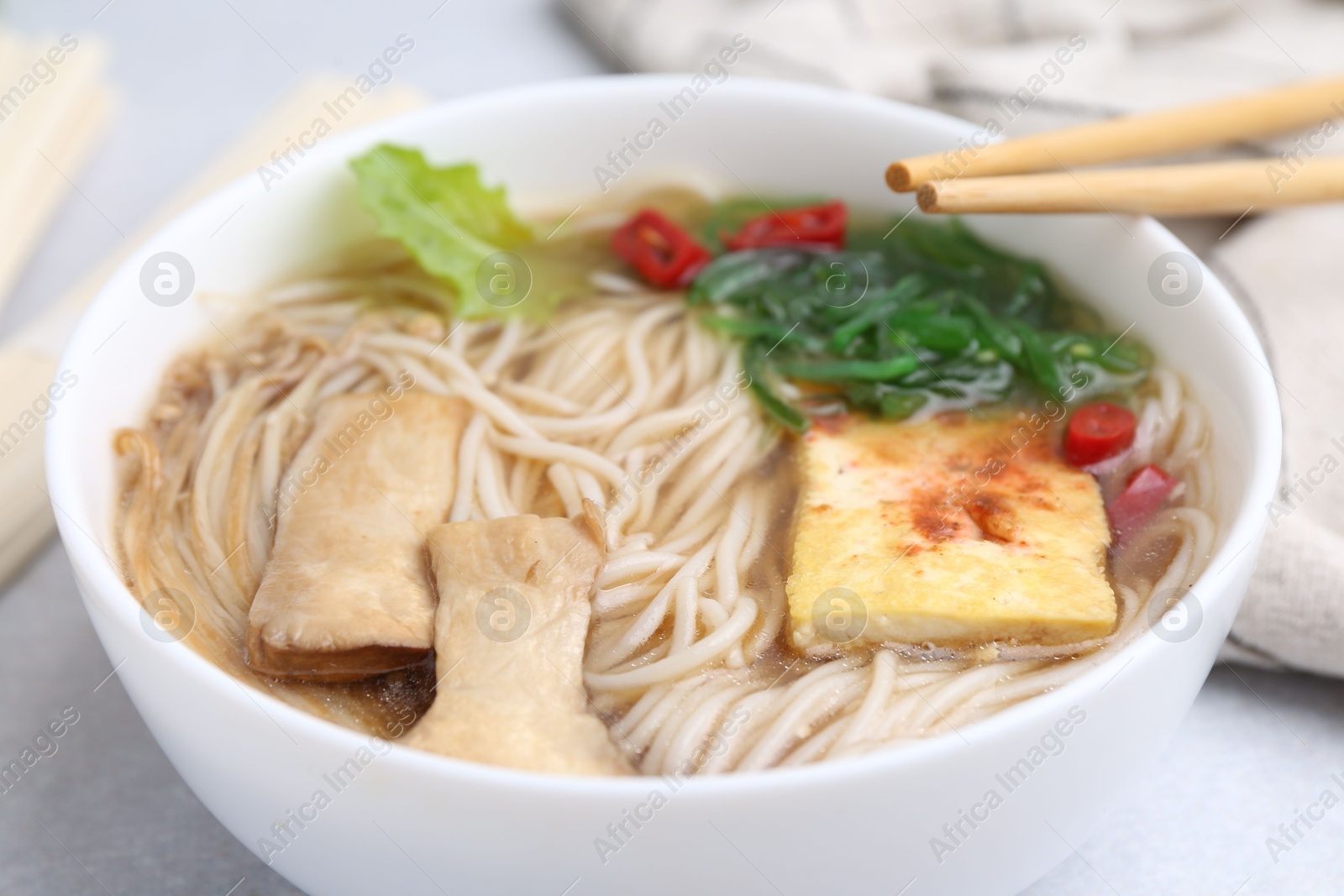 Tasty ramen with enoki and king oyster (eryngii) mushrooms on white table, closeup Photo of Tasty ramen with enoki and king oyster (eryngii) mushrooms on white table, closeup
