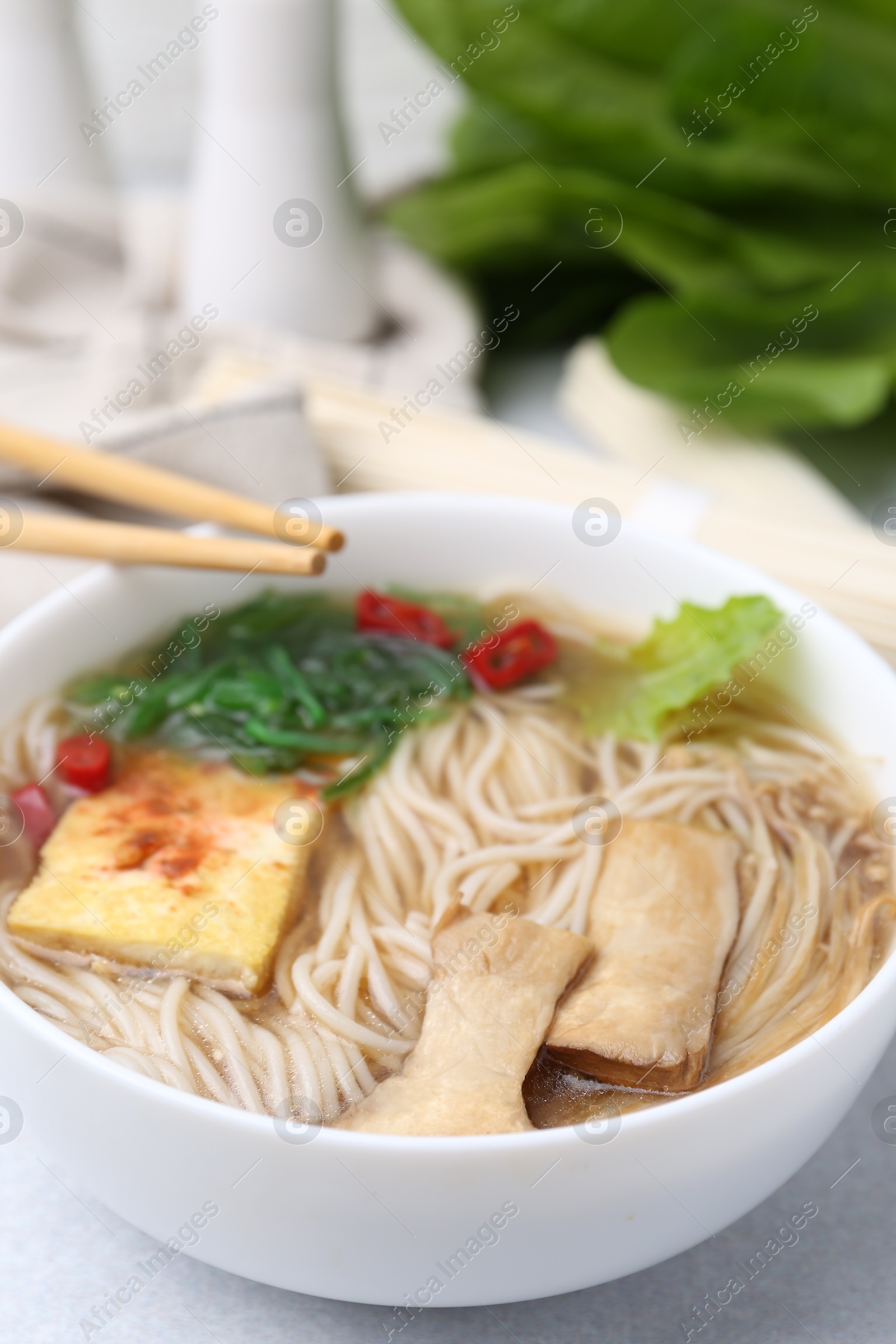 Tasty ramen with enoki and king oyster (eryngii) mushrooms on white table, closeup Photo of Tasty ramen with enoki and king oyster (eryngii) mushrooms on white table, closeup