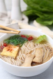 Photo of Tasty ramen with enoki and king oyster (eryngii) mushrooms on white table, closeup