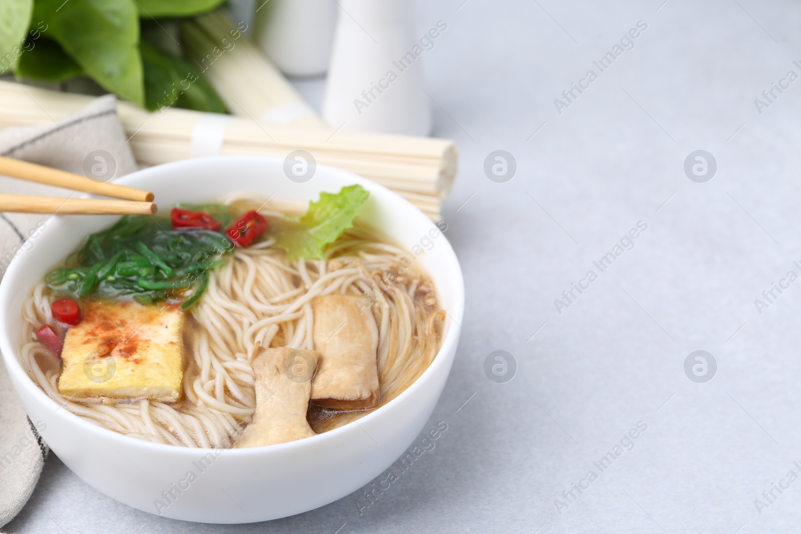 Tasty ramen with enoki and king oyster (eryngii) mushrooms on white table, closeup. Space for text Photo of Tasty ramen with enoki and king oyster (eryngii) mushrooms on white table, closeup. Space for text