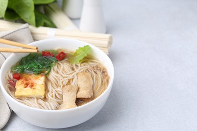 Photo of Tasty ramen with enoki and king oyster (eryngii) mushrooms on white table, closeup. Space for text