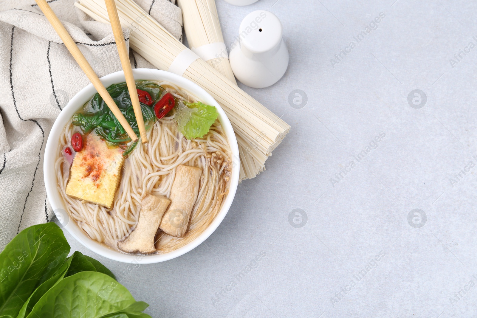 Tasty ramen with enoki and king oyster (eryngii) mushrooms on white table, flat lay. Space for text Photo of Tasty ramen with enoki and king oyster (eryngii) mushrooms on white table, flat lay. Space for text