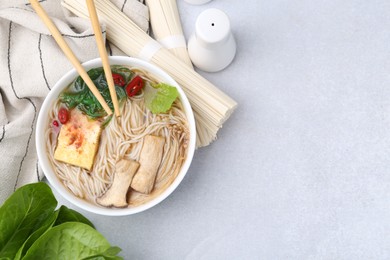 Photo of Tasty ramen with enoki and king oyster (eryngii) mushrooms on white table, flat lay. Space for text
