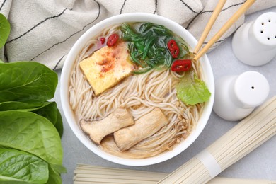 Photo of Tasty ramen with enoki and king oyster (eryngii) mushrooms on white table, flat lay