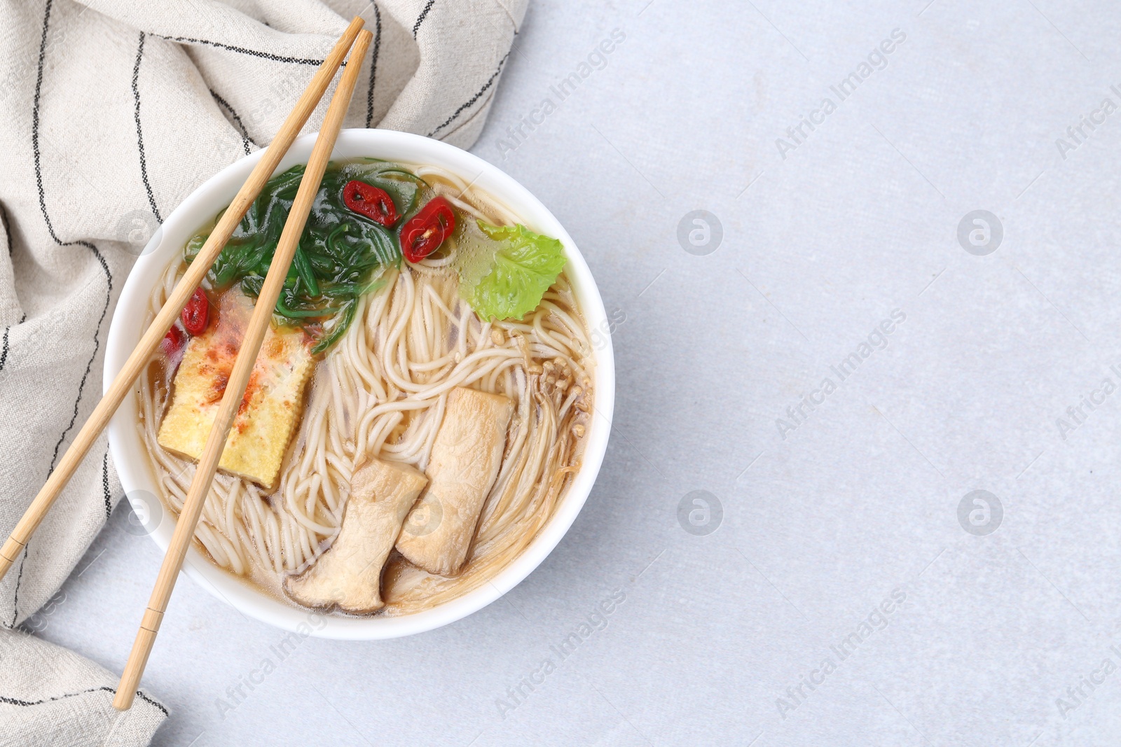 Tasty ramen with enoki and king oyster (eryngii) mushrooms on white table, top view Photo of Tasty ramen with enoki and king oyster (eryngii) mushrooms on white table, top view
