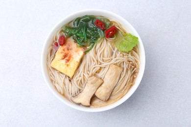 Photo of Tasty ramen with enoki and king oyster (eryngii) mushrooms on white table, top view