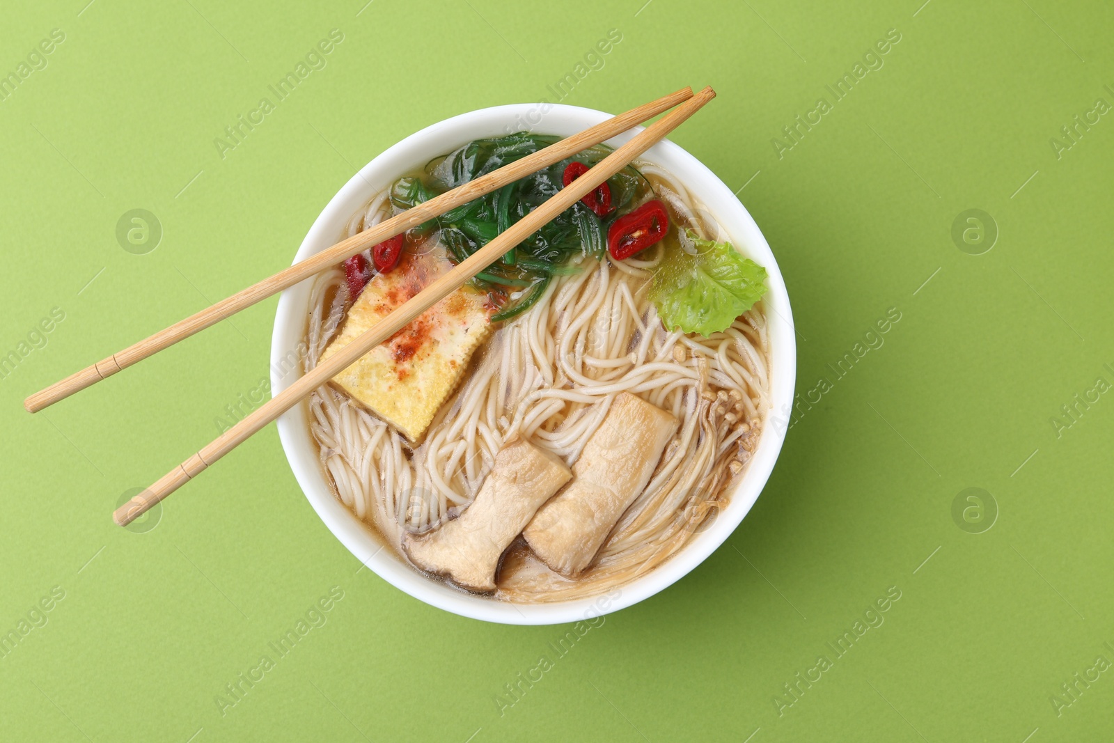 Tasty ramen with enoki and king oyster (eryngii) mushrooms on green background, top view Photo of Tasty ramen with enoki and king oyster (eryngii) mushrooms on green background, top view