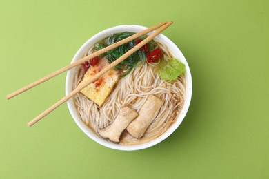 Photo of Tasty ramen with enoki and king oyster (eryngii) mushrooms on green background, top view