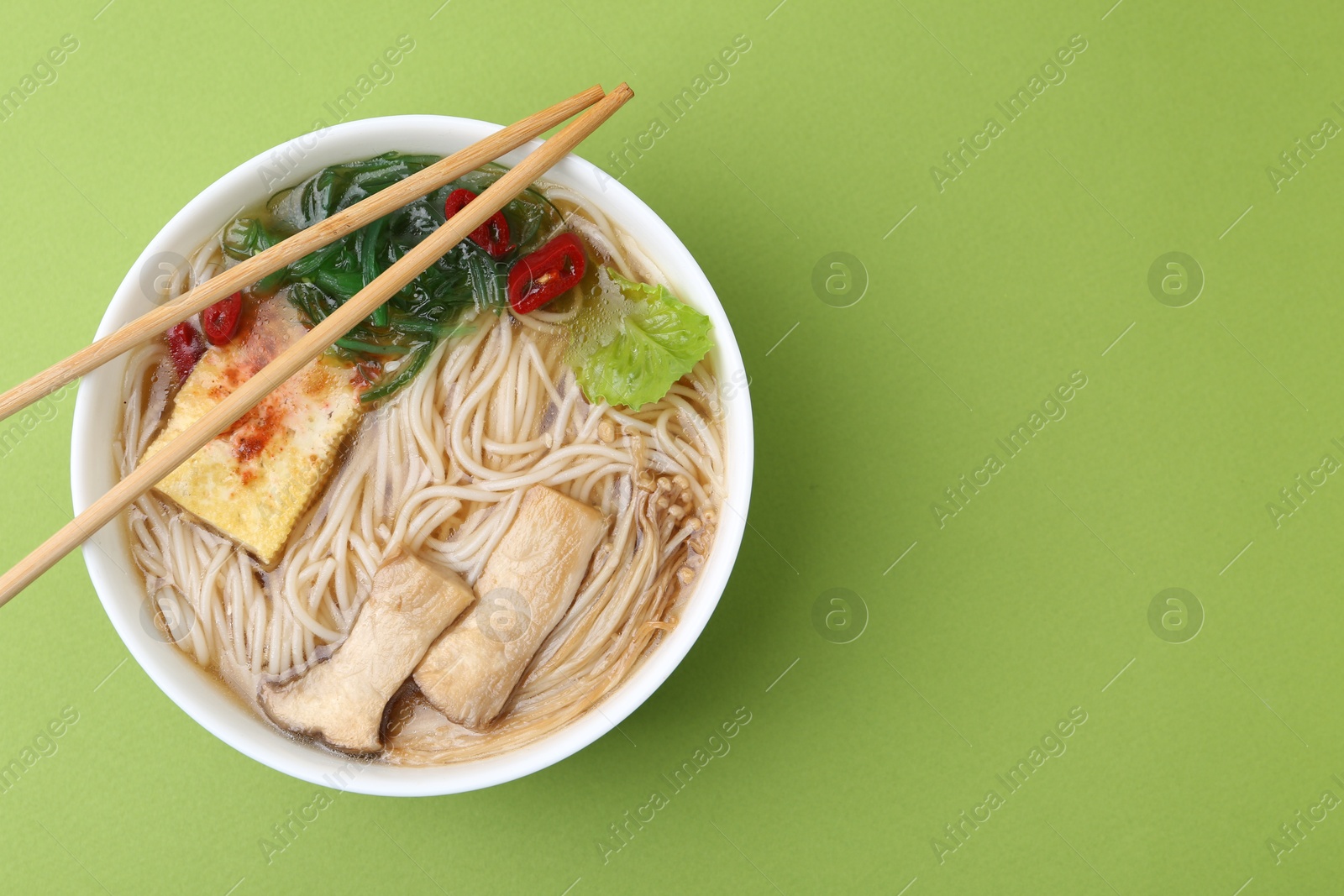 Tasty ramen with enoki and king oyster (eryngii) mushrooms on green background, top view. Space for text Photo of Tasty ramen with enoki and king oyster (eryngii) mushrooms on green background, top view. Space for text
