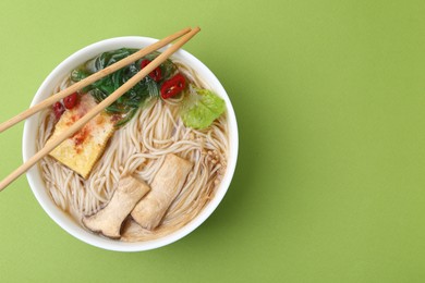 Photo of Tasty ramen with enoki and king oyster (eryngii) mushrooms on green background, top view. Space for text