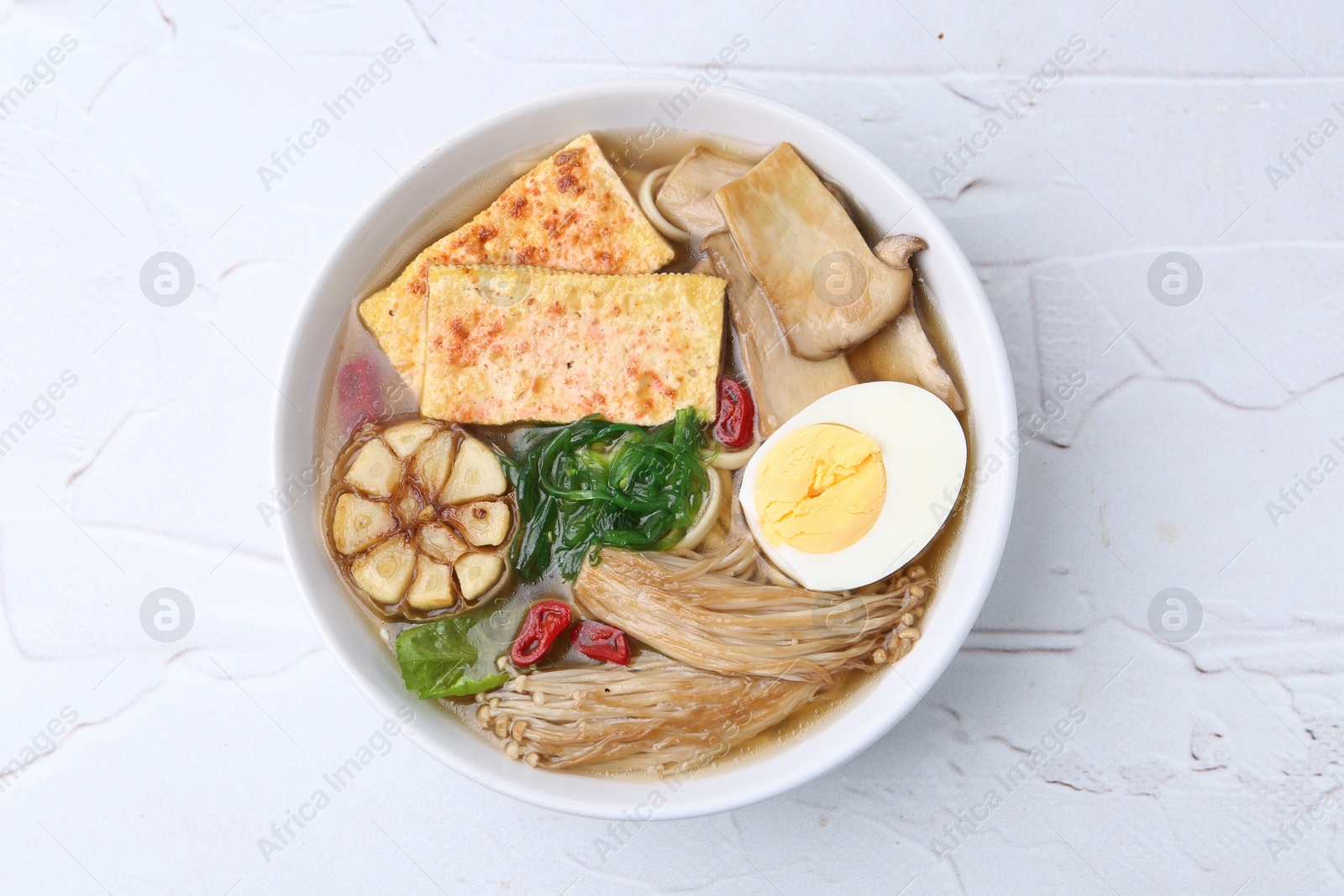 Tasty ramen with enoki and king oyster (eryngii) mushrooms on white table, top view Photo of Tasty ramen with enoki and king oyster (eryngii) mushrooms on white table, top view
