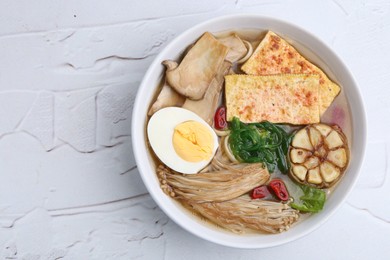 Photo of Tasty ramen with enoki and king oyster (eryngii) mushrooms on white table, top view. Space for text