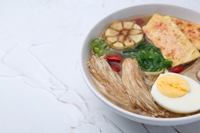 Photo of Tasty ramen with enoki and king oyster (eryngii) mushrooms on white table, closeup. Space for text