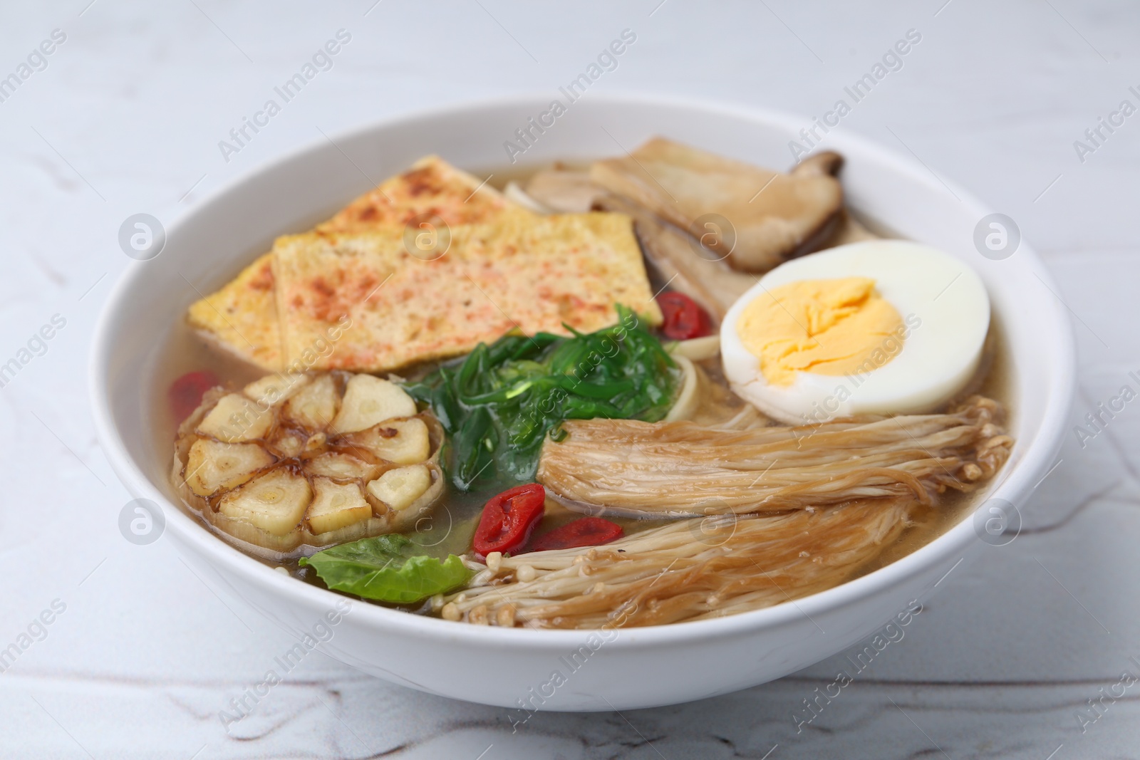Tasty ramen with enoki and king oyster (eryngii) mushrooms on white table, closeup Photo of Tasty ramen with enoki and king oyster (eryngii) mushrooms on white table, closeup