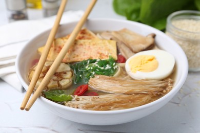 Photo of Tasty ramen with enoki and king oyster (eryngii) mushrooms on white table, closeup