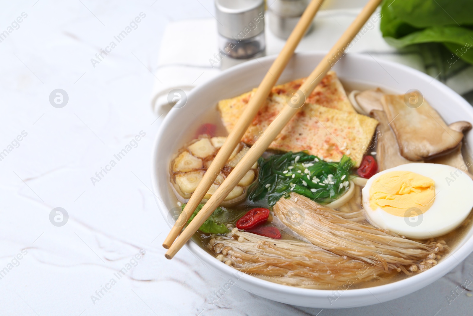 Tasty ramen with enoki and king oyster (eryngii) mushrooms on white table, closeup. Space for text Photo of Tasty ramen with enoki and king oyster (eryngii) mushrooms on white table, closeup. Space for text
