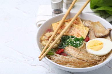 Photo of Tasty ramen with enoki and king oyster (eryngii) mushrooms on white table, closeup. Space for text