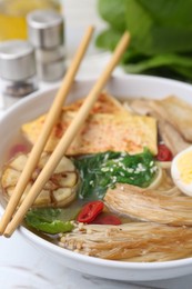 Photo of Tasty ramen with enoki and king oyster (eryngii) mushrooms on white table, closeup