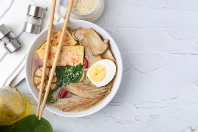 Photo of Tasty ramen with enoki and king oyster (eryngii) mushrooms on white table, flat lay. Space for text