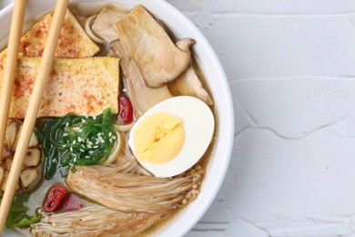 Photo of Tasty ramen with enoki and king oyster (eryngii) mushrooms on white table, top view. Space for text