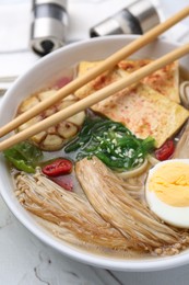 Photo of Tasty ramen with enoki and king oyster (eryngii) mushrooms on white table, closeup