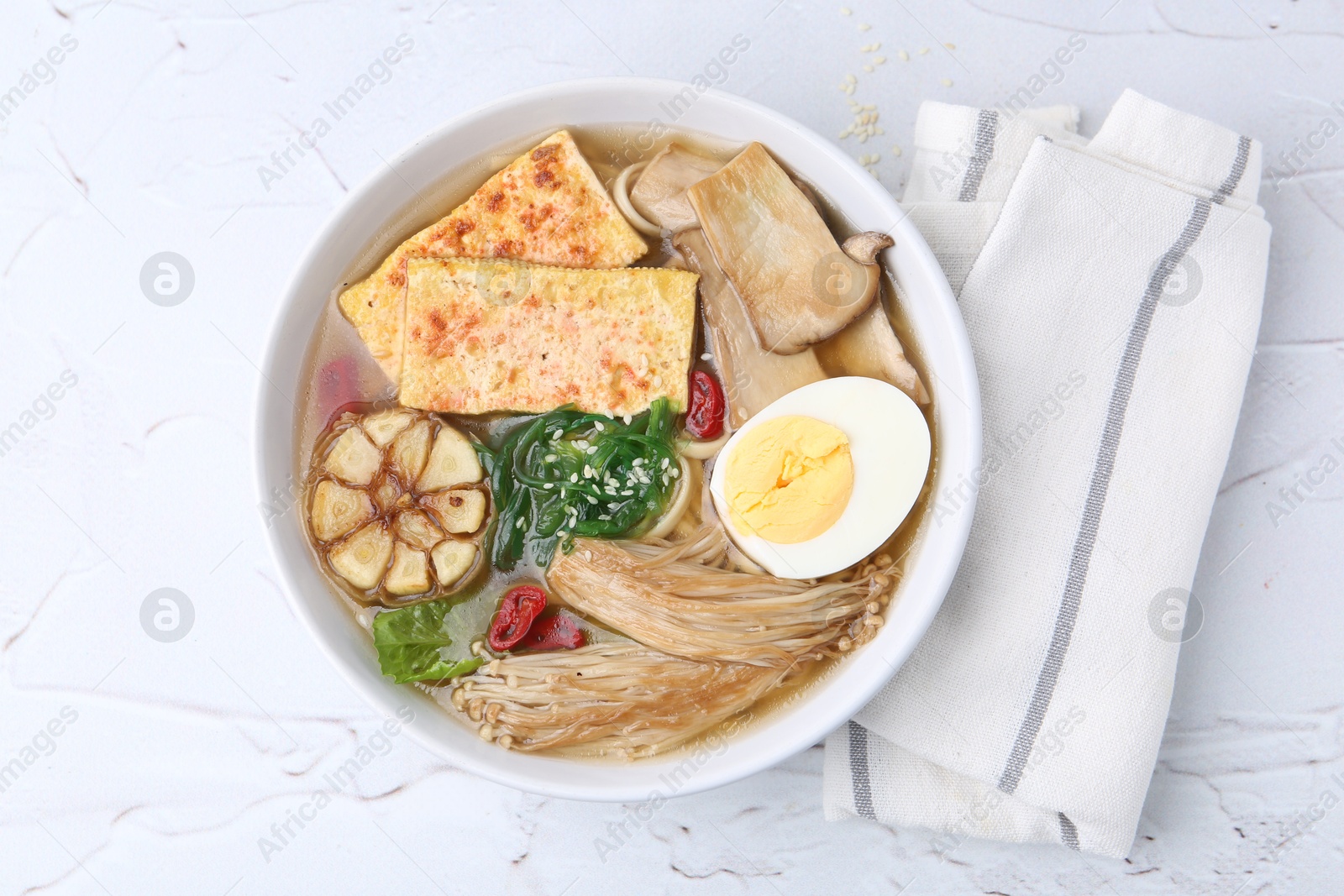 Tasty ramen with enoki and king oyster (eryngii) mushrooms on white table, top view Photo of Tasty ramen with enoki and king oyster (eryngii) mushrooms on white table, top view