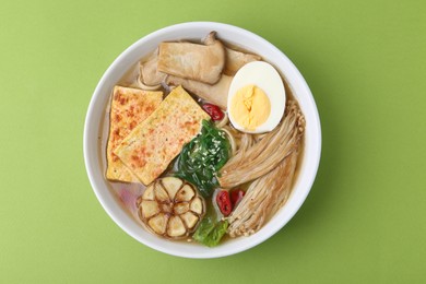 Photo of Tasty ramen with enoki and king oyster (eryngii) mushrooms on green background, top view