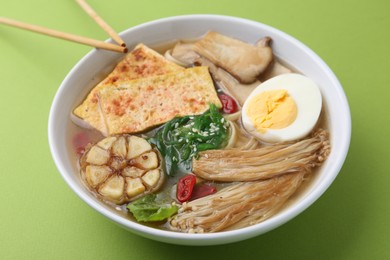 Photo of Tasty ramen with enoki and king oyster (eryngii) mushrooms on green background, closeup