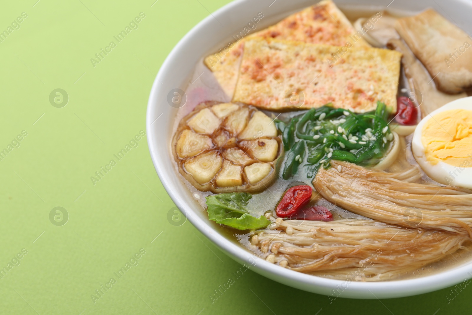 Tasty ramen with enoki and king oyster (eryngii) mushrooms on green background, closeup. Space for text Photo of Tasty ramen with enoki and king oyster (eryngii) mushrooms on green background, closeup. Space for text