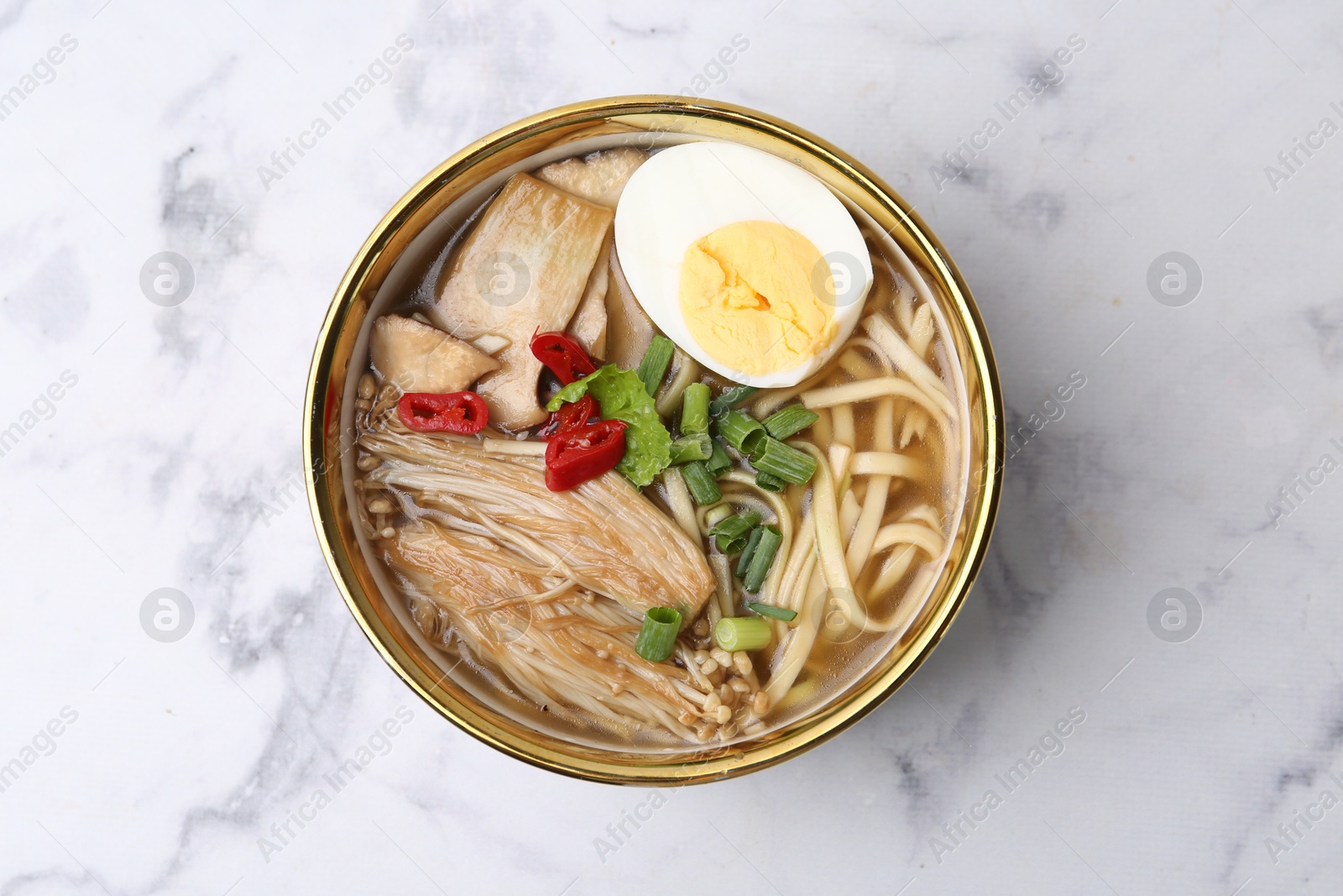Tasty ramen with enoki and king oyster (eryngii) mushrooms on white marble table, top view Photo of Tasty ramen with enoki and king oyster (eryngii) mushrooms on white marble table, top view